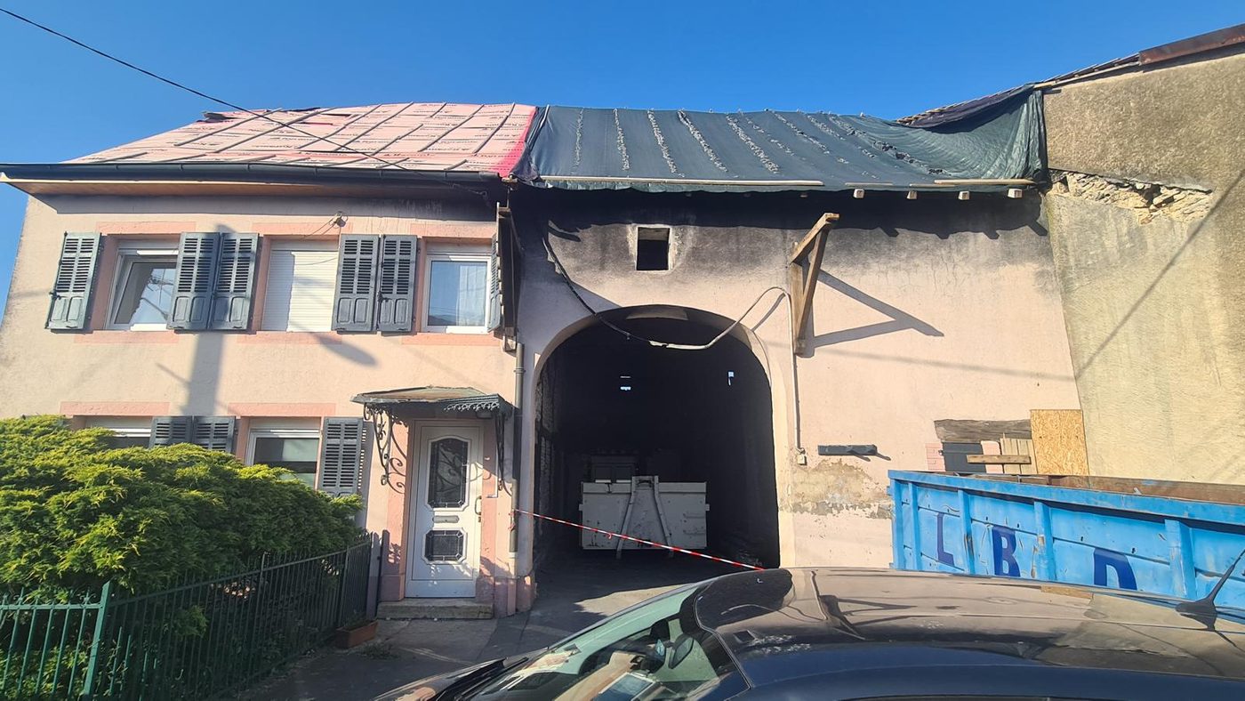 Façade d'une maison de village avant travaux, enduit rose défraîchi et porche en cours de reprise