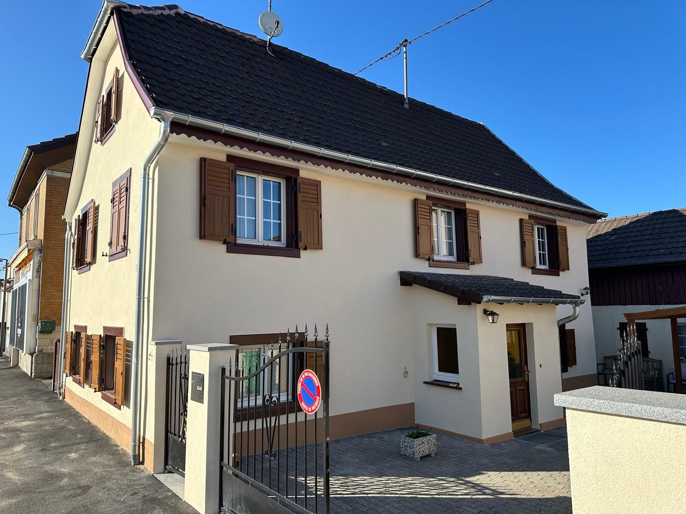 Maison de village avec volets bois après rénovation, enduit crème lisse