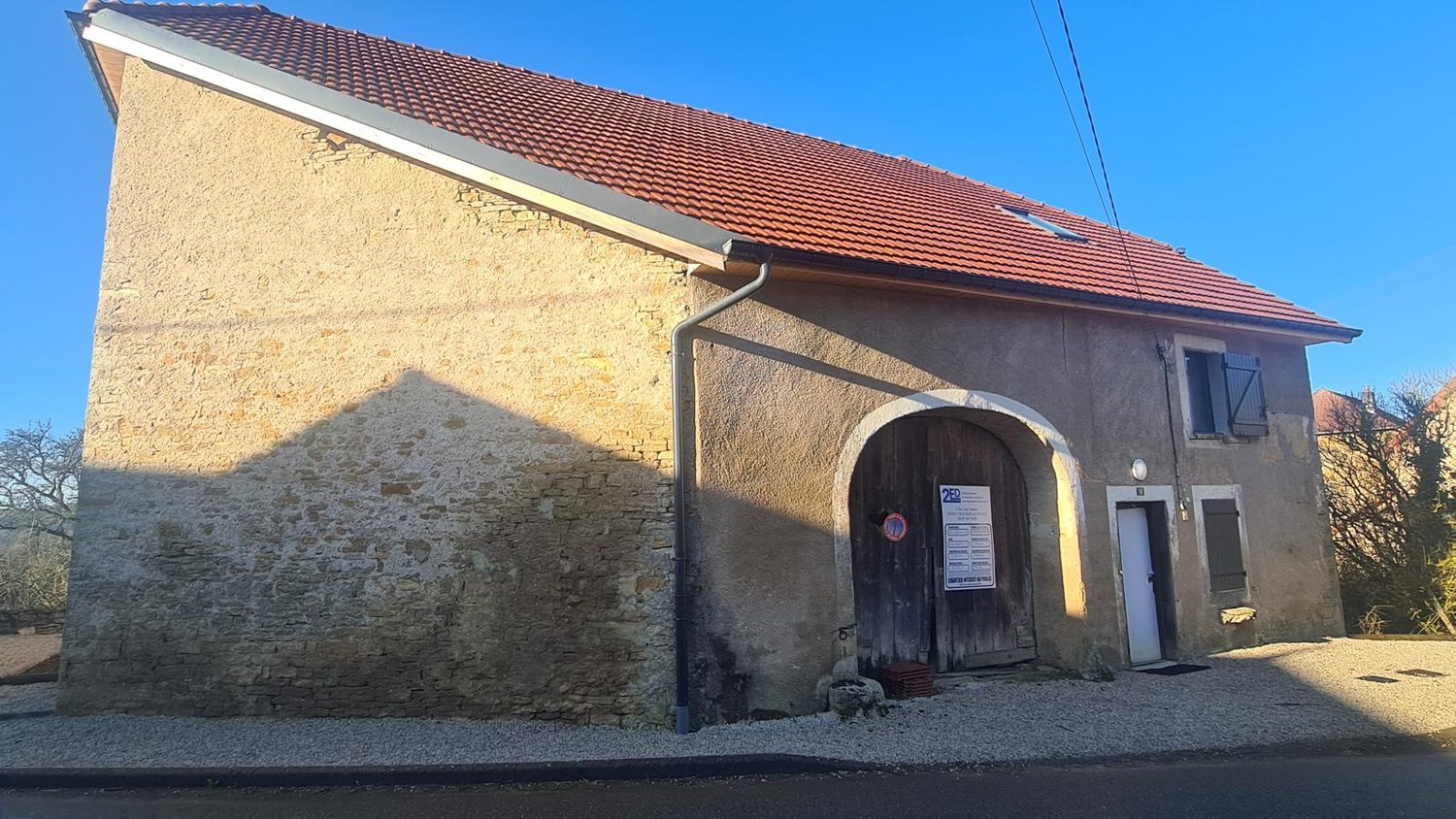 Façade d'une grange en pierre avant travaux, ancien enduit ciment dégradé autour du porche